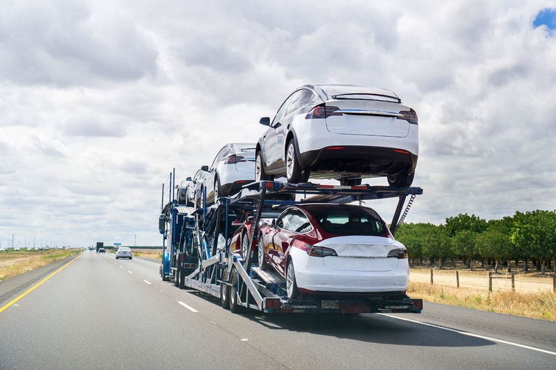 a cross-country moving vehicle transporting cars on an open trailer