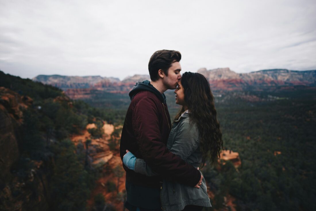 Romantic moment captured: A young couple sharing a kiss with a breathtaking view in the background.