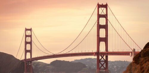 Golden Gate Bridge bathed in the warm hues of a stunning sunset in San Francisco. The iconic landmark spans across the water, silhouetted against the radiant sky, creating a breathtaking and tranquil scene.