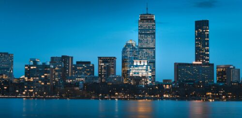 Under the night sky, the city of Boston comes alive with a captivating river view. The twinkling lights of the town reflect on the calm waters, outlining the silhouette of the skyline. The nocturnal charm of Boston unfolds along the river, offering a picturesque and enchanting scene that captures the city's unique ambiance in the quietude of the night