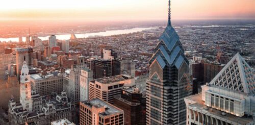 Aerial view of Philadelphia, showcasing the cityscape under a vast sky. Skyscrapers, historic landmarks, and urban architecture blend together in this dynamic skyline, capturing the essence of Philadelphia from a bird's-eye perspective.