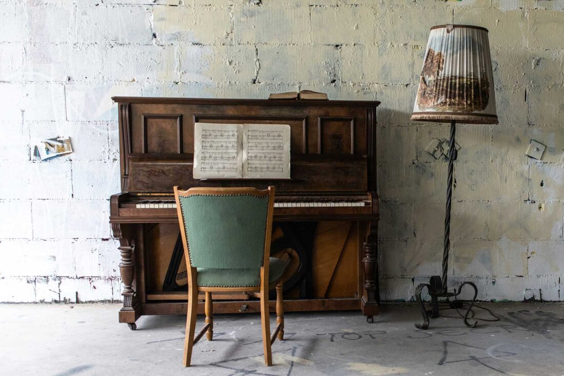 brown upright piano beside gray floor lamp