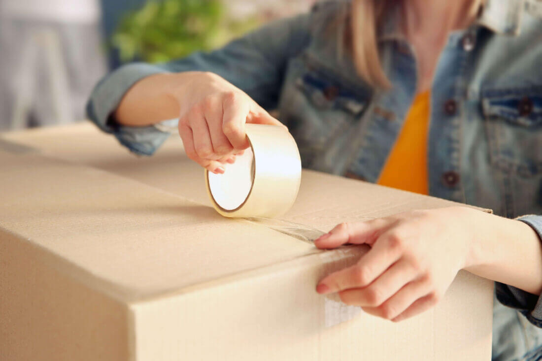 A person sealing a box with tape
