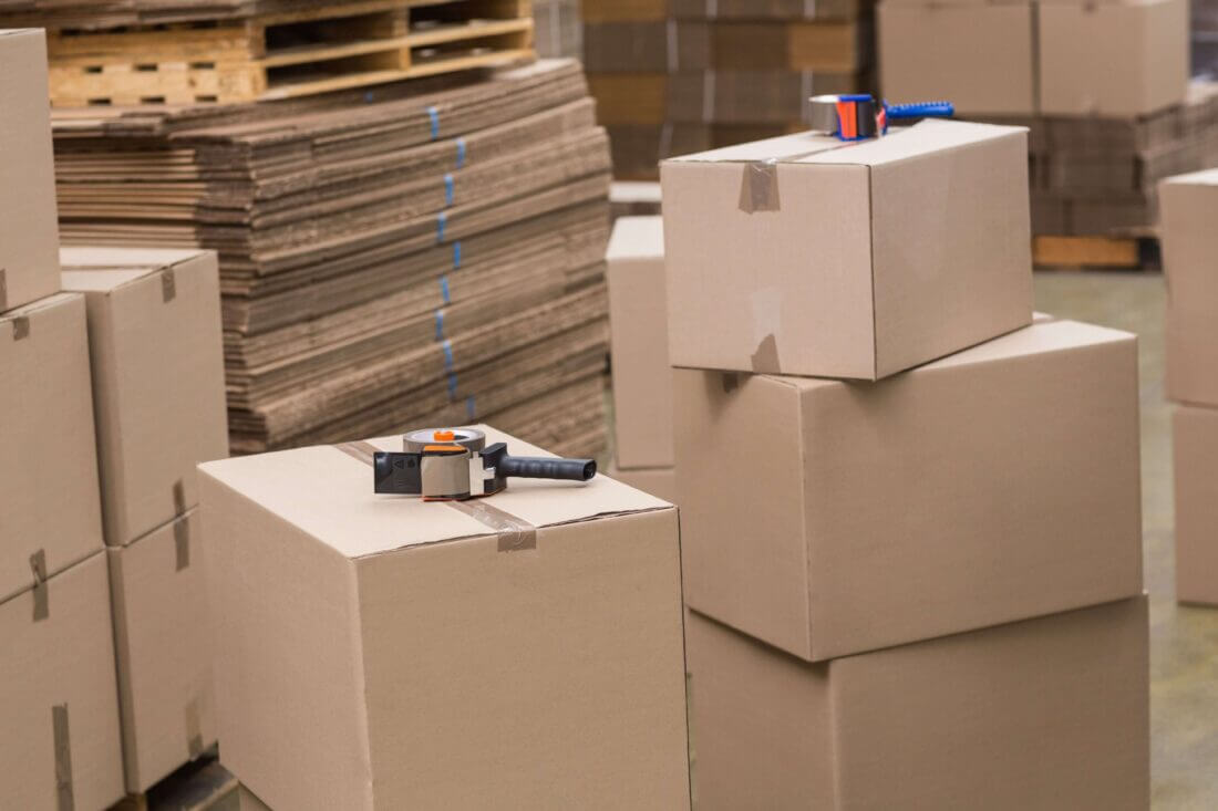 Some boxes stacked on top of each other, with a bunch of cardboard in the back