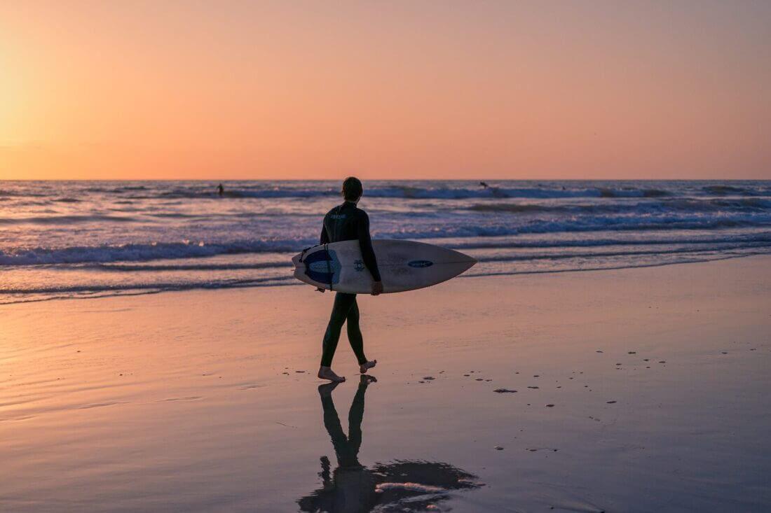 A surfer on the beach in sunset