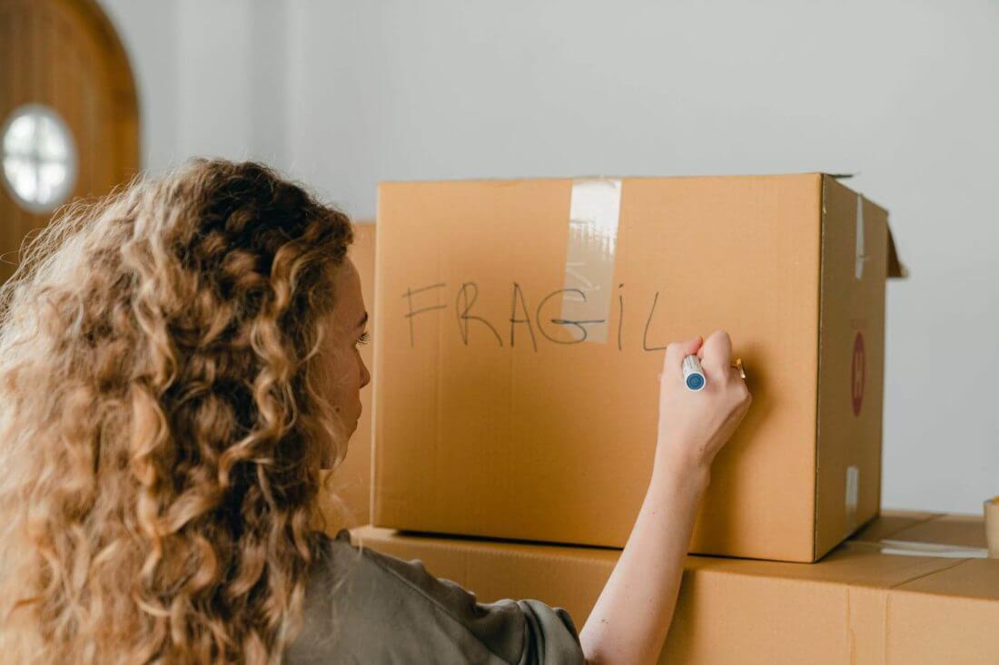 A girl labeling a carton with a marker