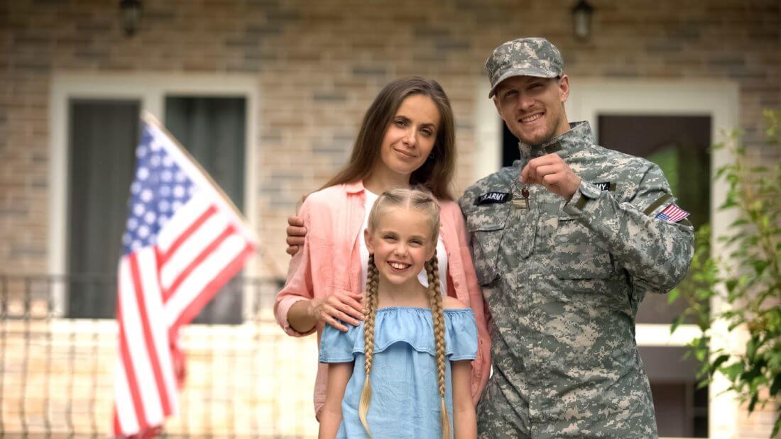 American family in front of their house, with a military member holding keys