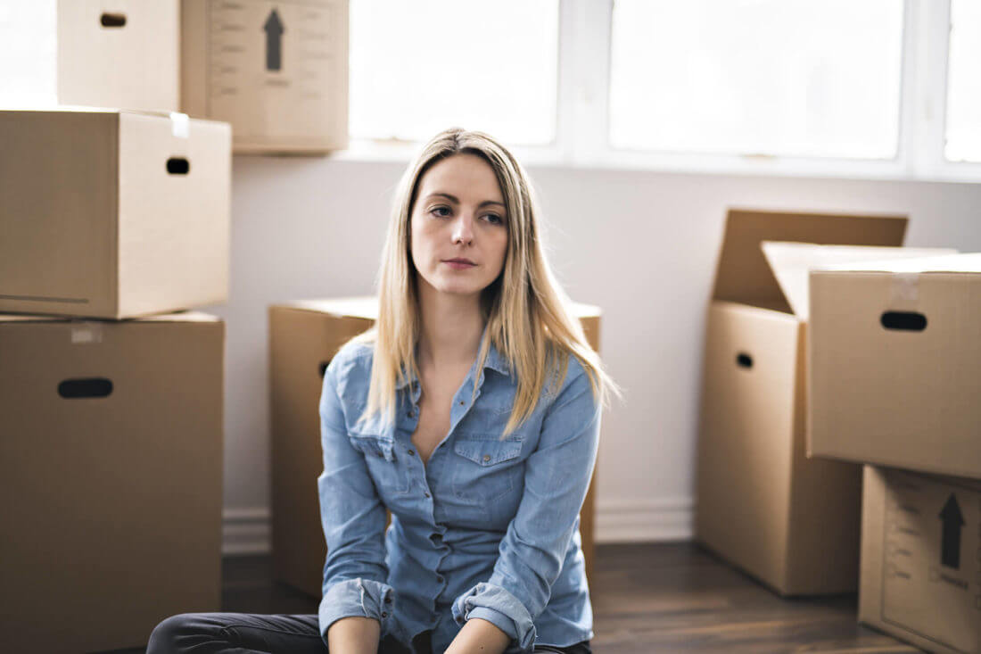 a girl sitting among boxes after long-distance moving