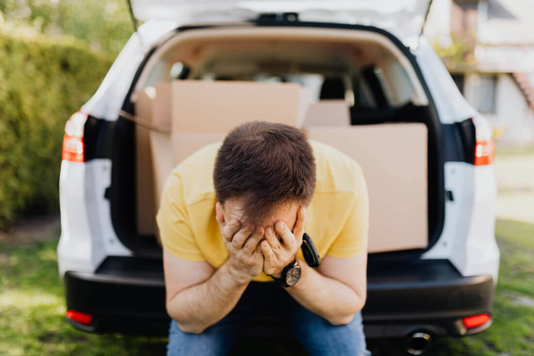 Tired and worried man sitting in a trunk of a car before long-distance moving