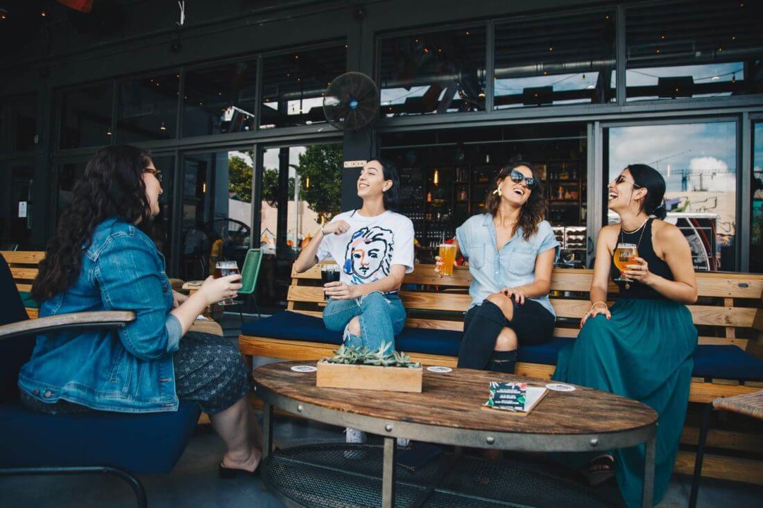 Four women in the bar laughing after long distance moving