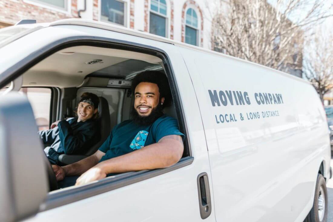 professional movers driving a white minivan with a logo of long-distance moving services