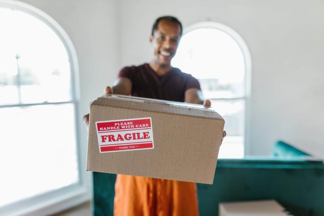 a man holding a labeled box with fragile items ready to unpack after long-distance moving