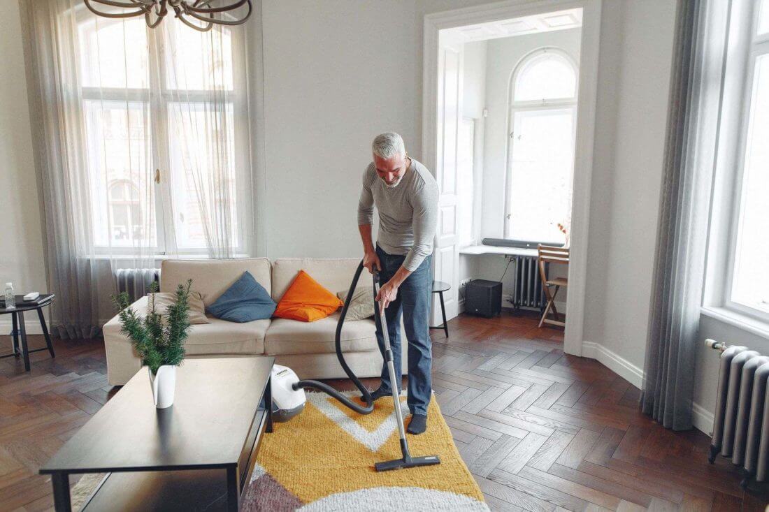 man vacuuming the living room after cross-country moving 