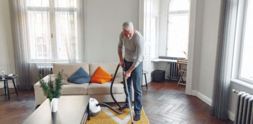 man vacuuming the living room after cross-country moving