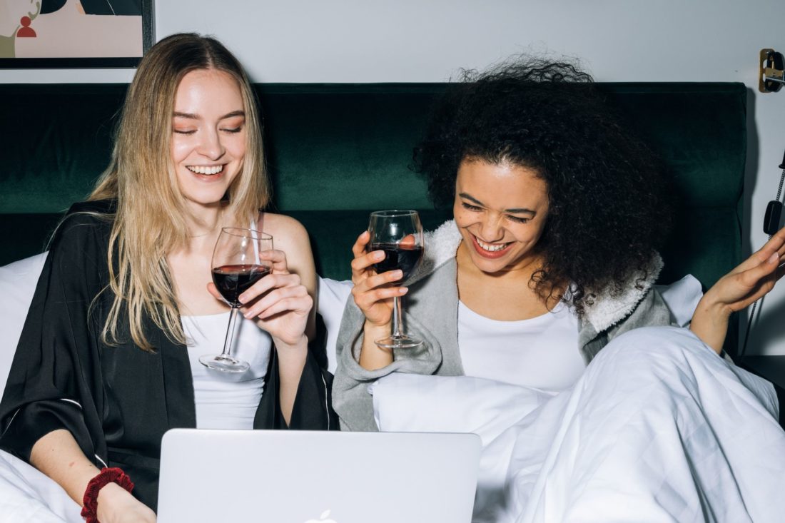 Two girls drinking wine and smiling after cross-country moving