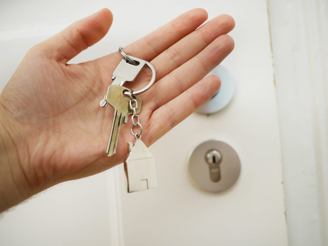 a man is holding keys to the house he bought after a long-distance moving 