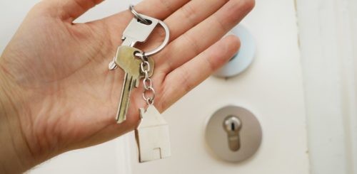 a man is holding keys to the house he bought after a long-distance moving