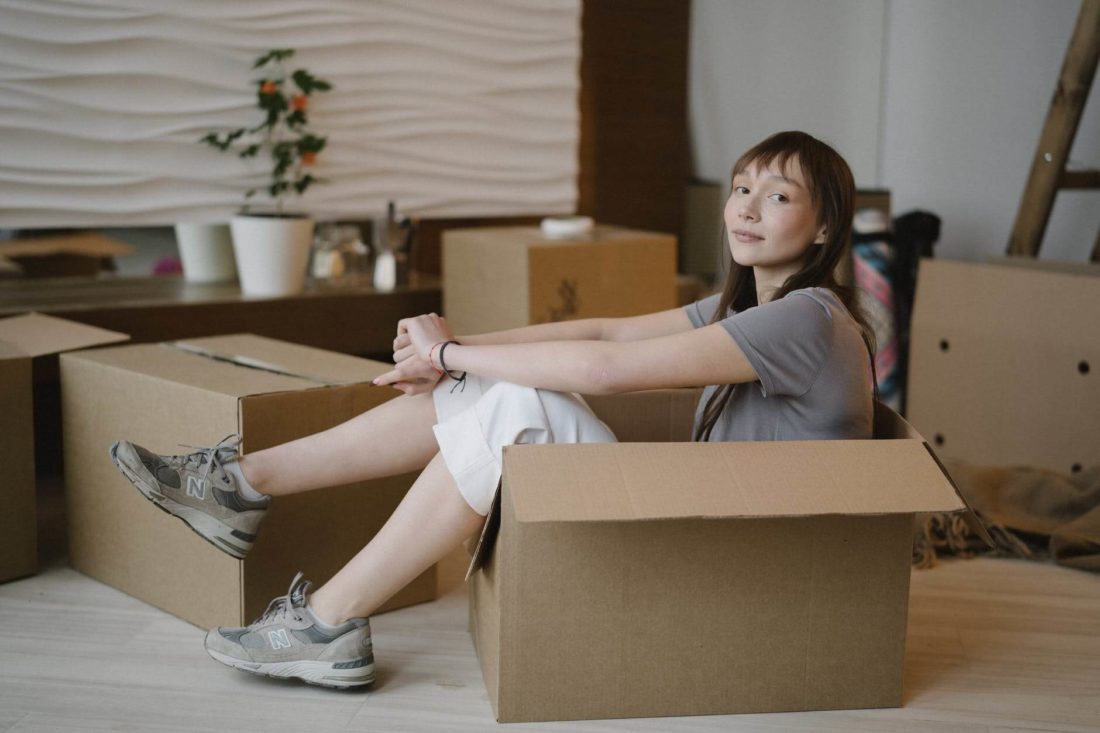 Woman sitting inside the box before long-distance moving