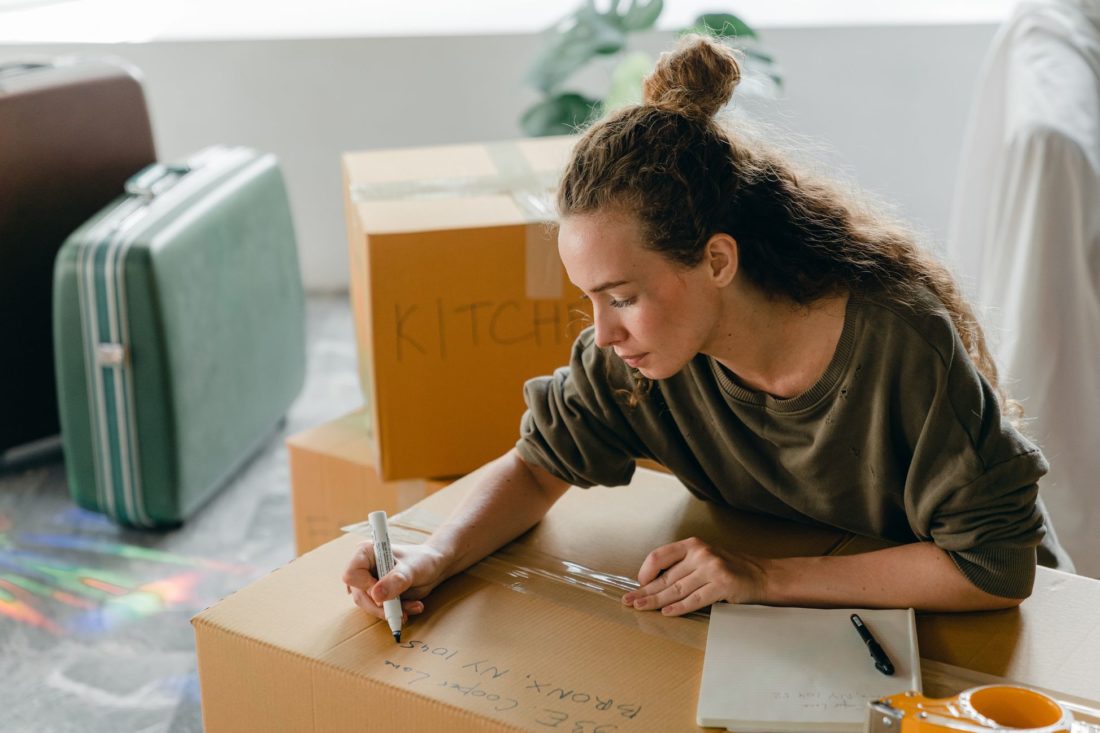 A girl labeling a long-distance moving box with a marker