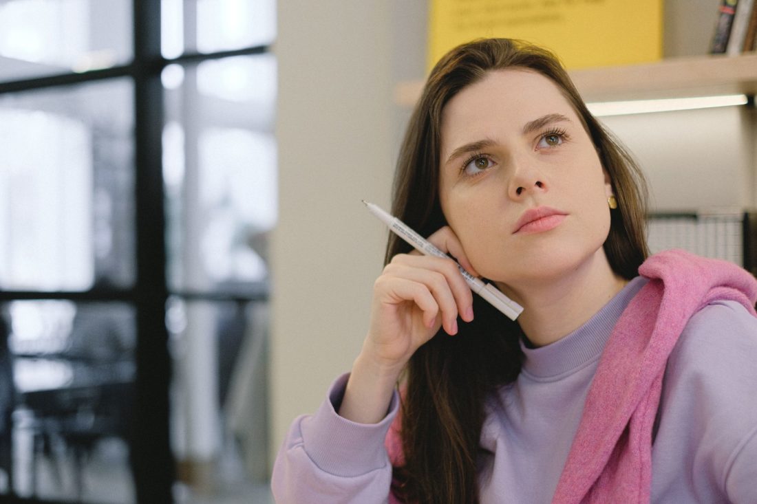 A girl holding a pen and thinking about long-distance moving services 