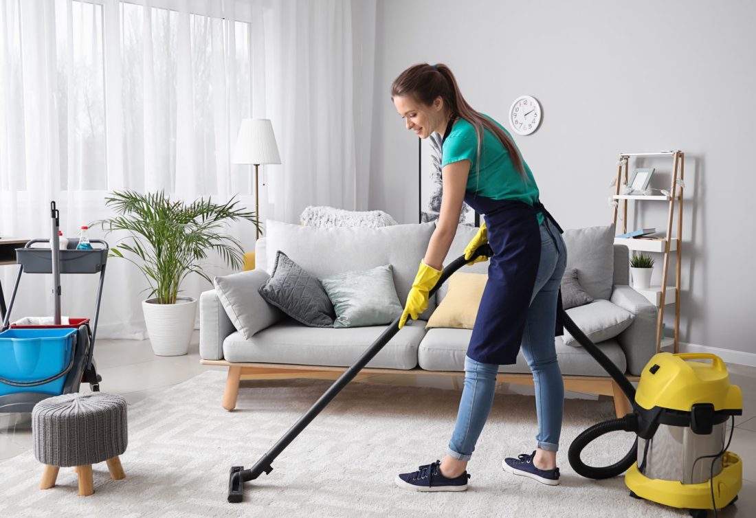 Woman vacuum cleans the house