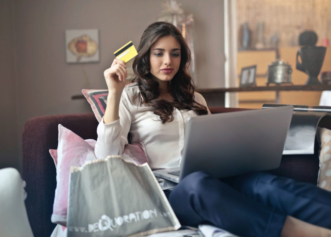 A woman holding a credit card while online shopping on a laptop