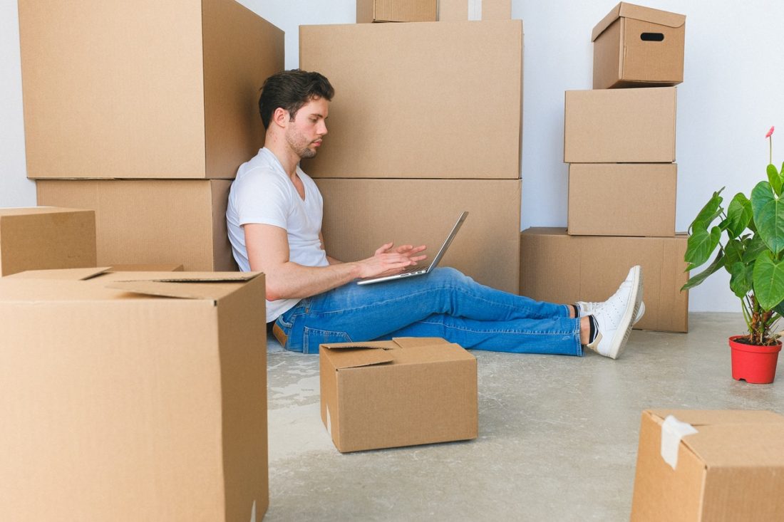 Man is sitting on the floor surrounded with packed cardboard boxes