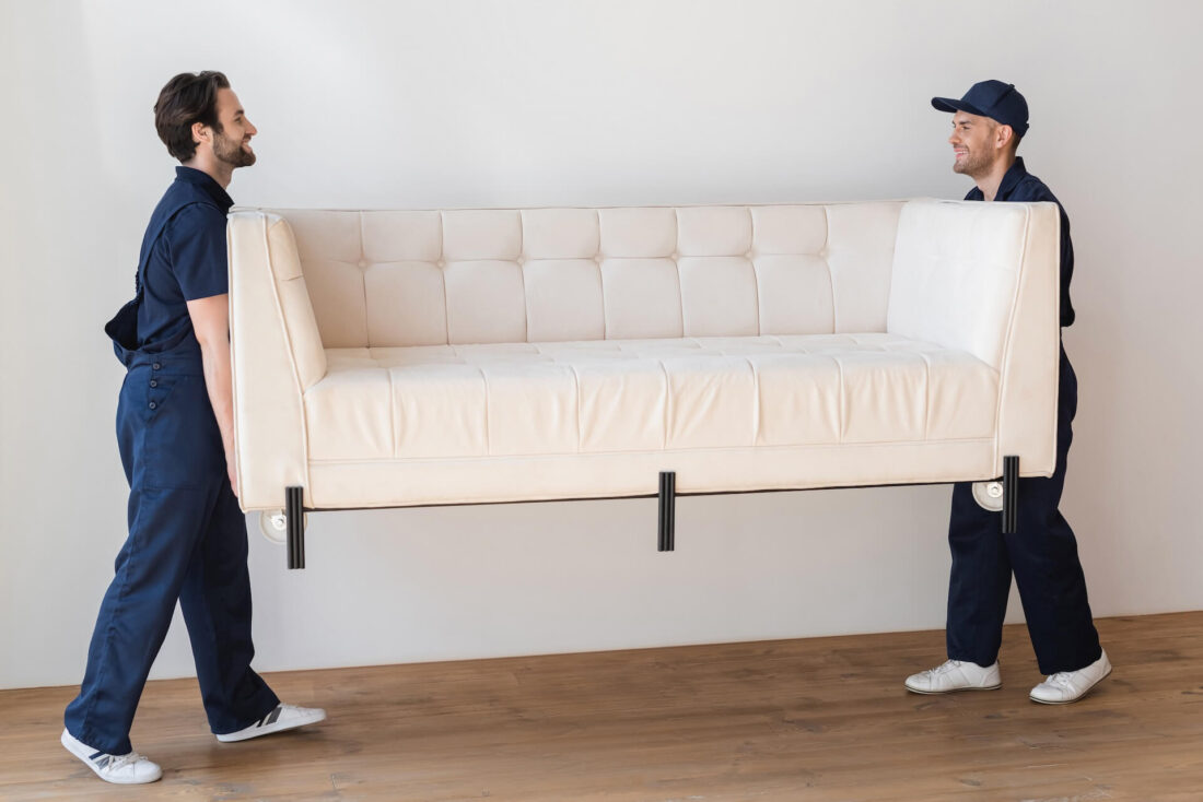 Two cross-country movers carrying a sofa