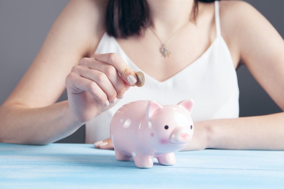 woman is putting coins in the piggy bank getting ready for cross-country moving