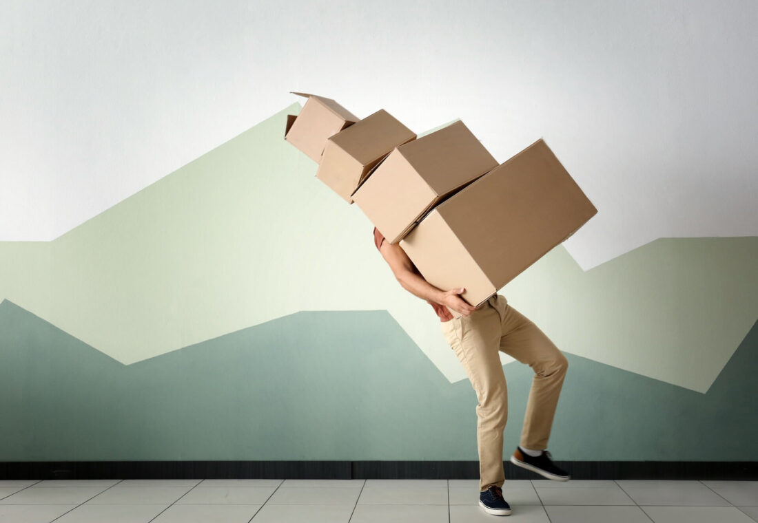 A man carrying four boxes of different sizes stacked onto each other