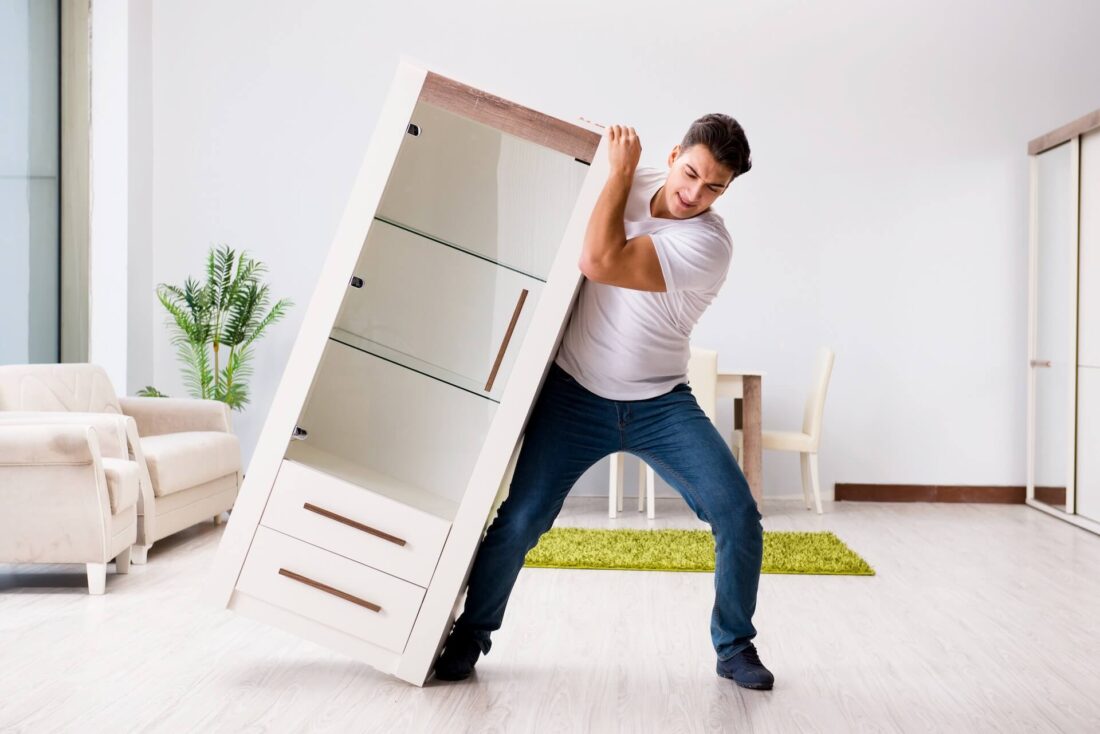 A man trying to move a cupboard