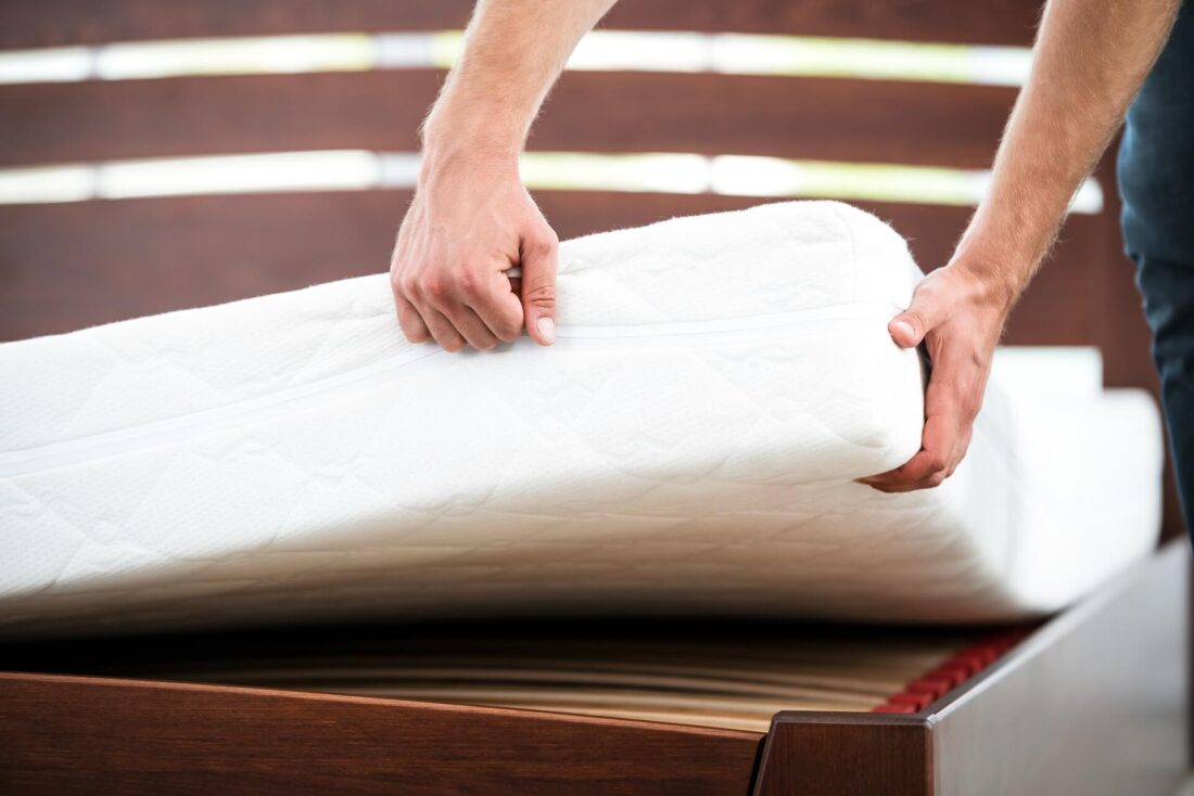 A man lifting the corner of a mattress