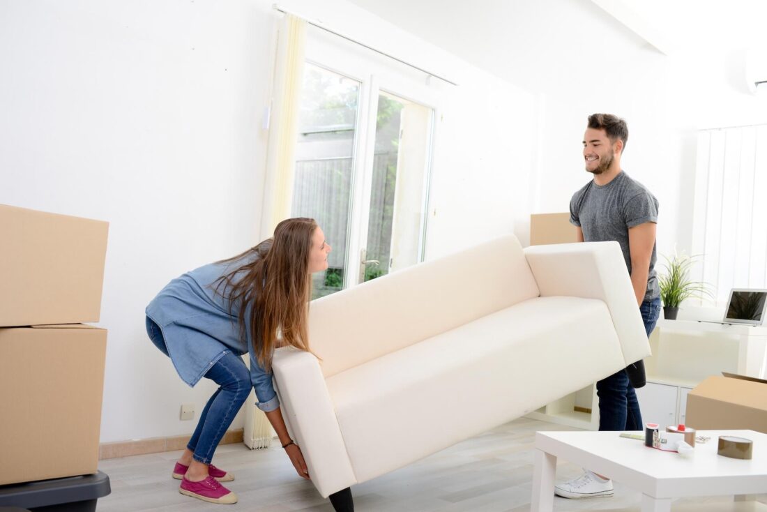 A woman and a man lifting a sofa before long-distance moving