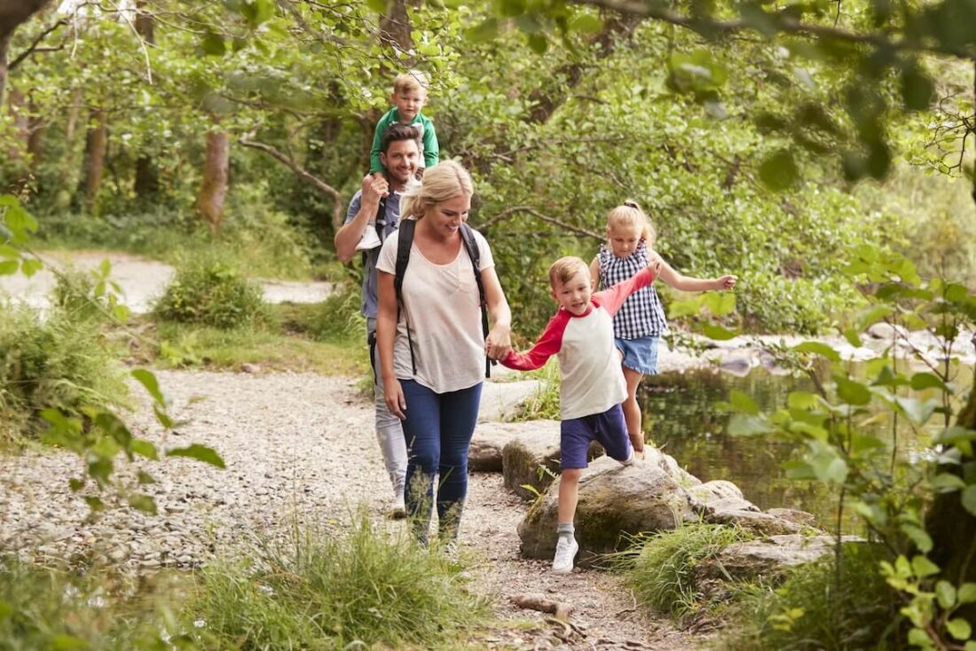 Parents walking through woods with their kids and enjoying the environment.
