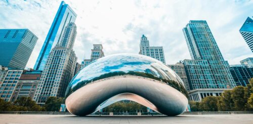 Iconic metal monument in Chicago's Millennium Park, 'Cloud Gate' reflects the city skyline. The polished stainless steel surface of the sculpture glistens, inviting visitors to interact with its unique form and experience the beauty of Chicago's urban landscape