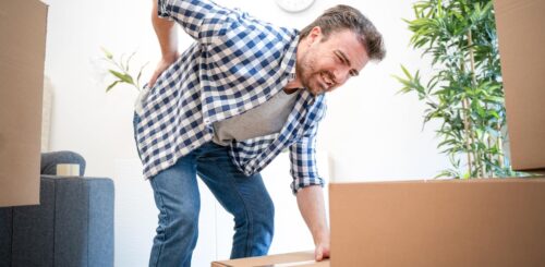 A man is in pain while trying to lift a box