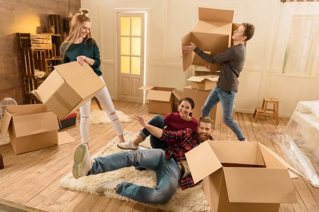 People smiling and carrying boxes before long-distance moving company comes