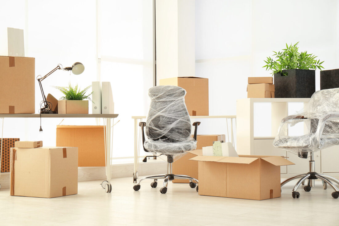 Two chairs wrapped in plastic wrap and boxes in an office ready for long-distance moving