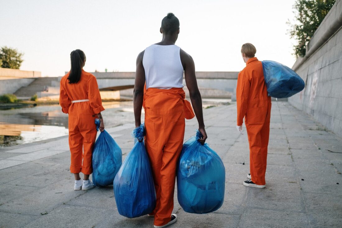 Three people in orange carrying bags