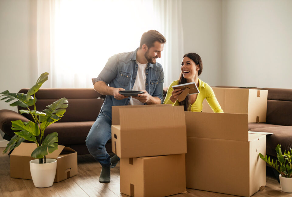 Smiling couple unpaking boxes in new home