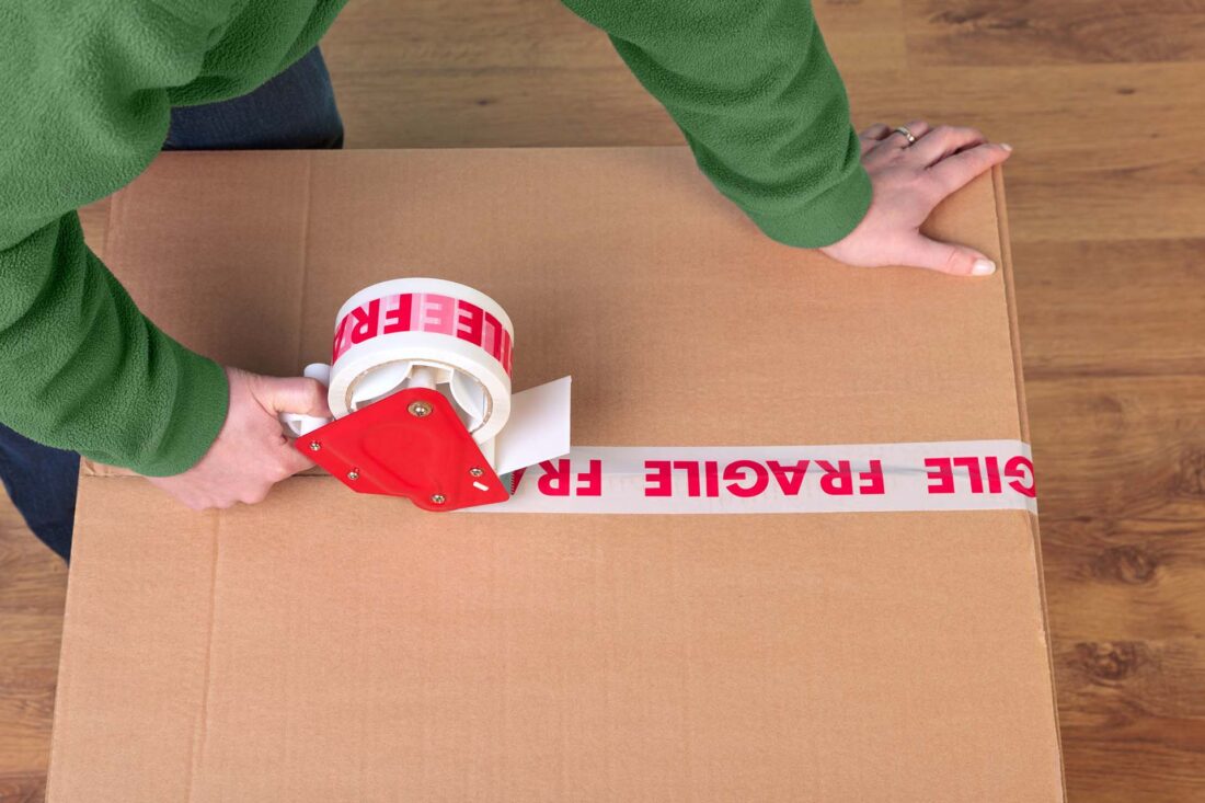 Person closing a box with a fragile label on it